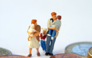 Miniatur einer Familie läuft zwischen Geldmünzen von S. Hofschlaeger / pixelio.de