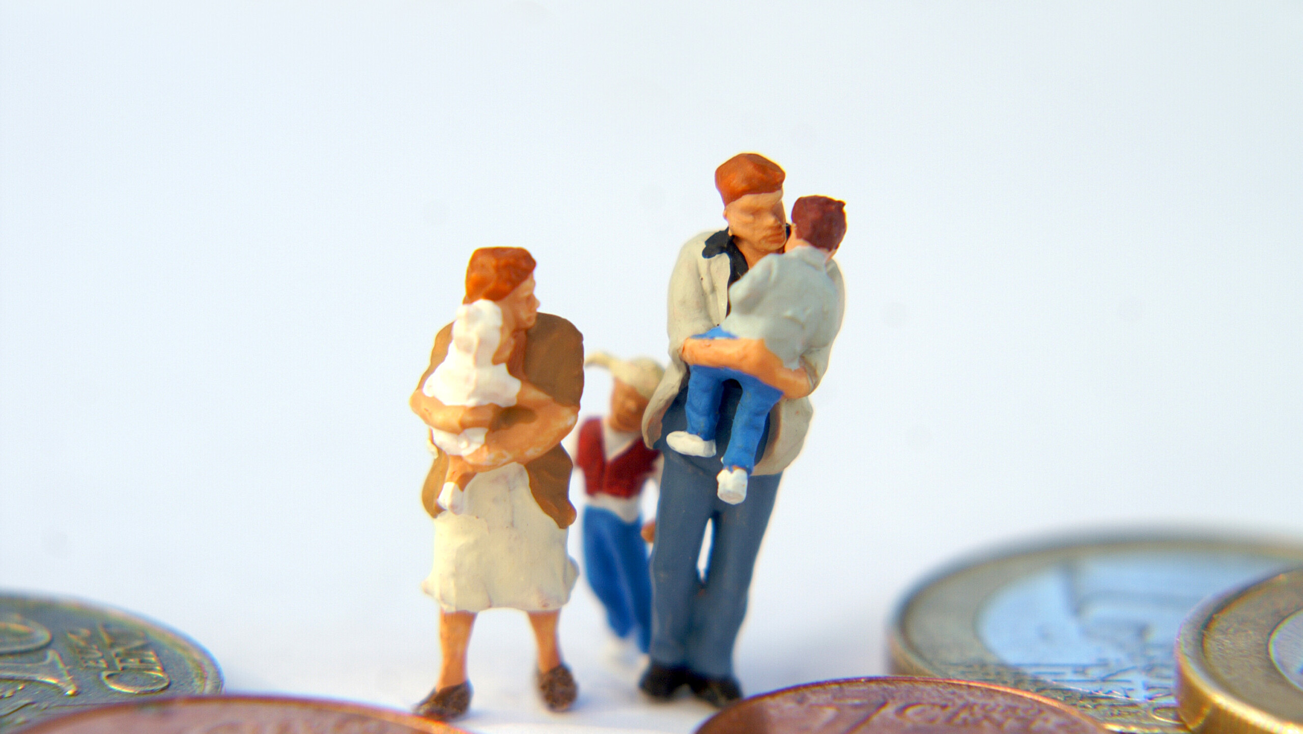Miniatur einer Familie läuft zwischen Geldmünzen von S. Hofschlaeger / pixelio.de
